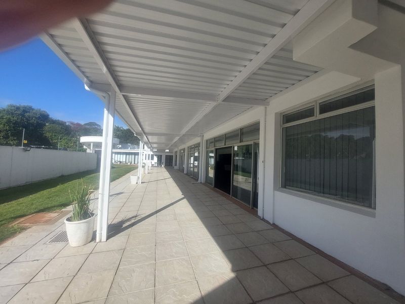 A spacious covered patio area featuring tiled flooring, a metal roof structure, and extensive sliding glass door access to the commercial building interior.