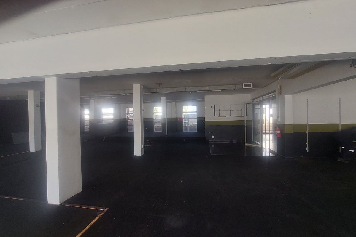 A large, open-plan commercial space featuring structural support columns, exposed ceilings, and multiple glass entry points, suitable for various business or retail configurations.