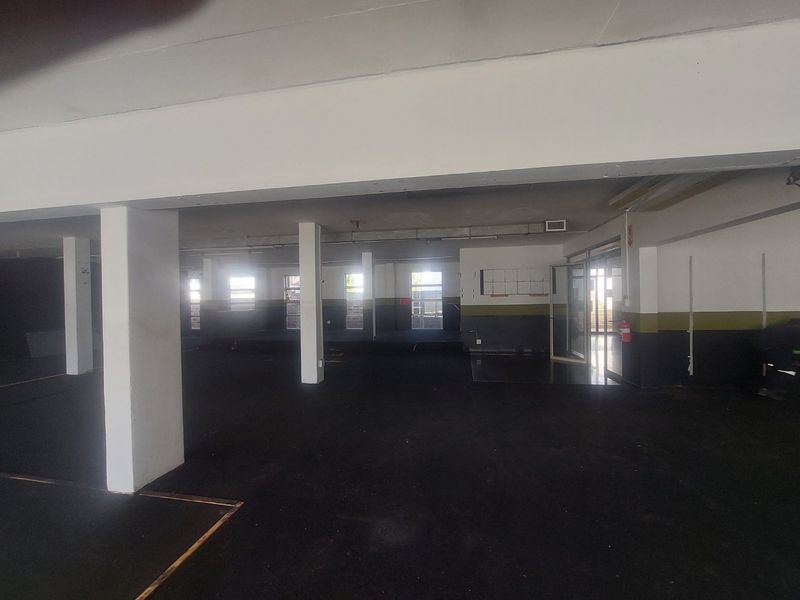 A large, open-plan commercial space featuring structural support columns, exposed ceilings, and multiple glass entry points, suitable for various business or retail configurations.