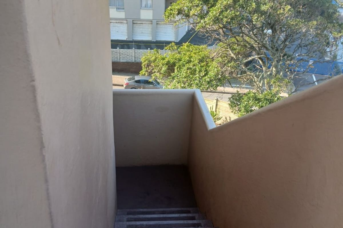 An outdoor concrete staircase providing access to the apartment, featuring a view of the surrounding neighborhood and nearby buildings.