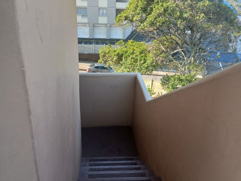 An outdoor concrete staircase providing access to the apartment, featuring a view of the surrounding neighborhood and nearby buildings.
