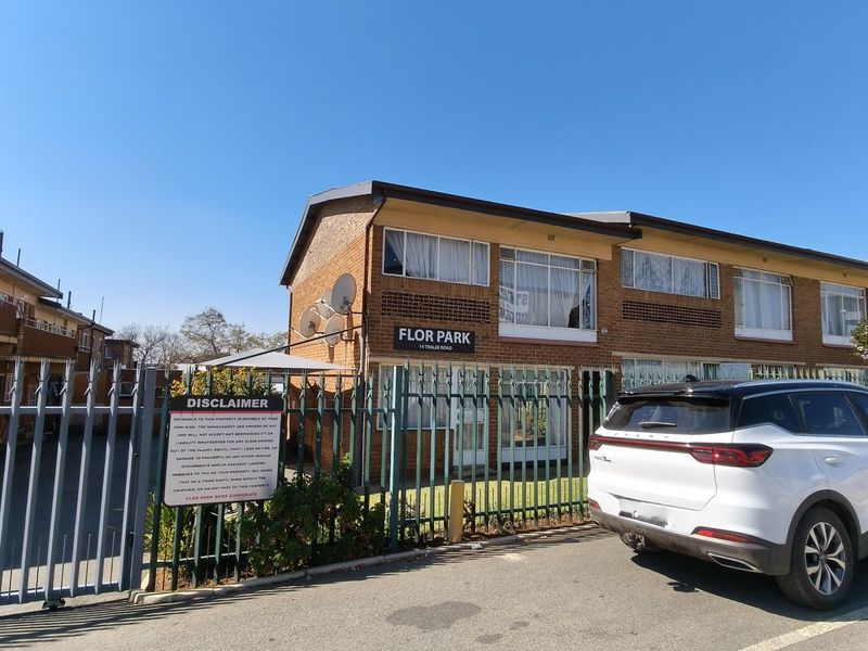 Front exterior view of the Flor Park apartment complex, featuring brick facade, security fencing, and established residential building structure.