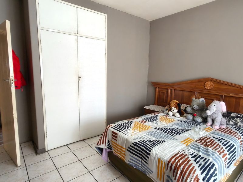A bedroom featuring tiled flooring and a built-in wardrobe, providing functional storage space within the apartment.