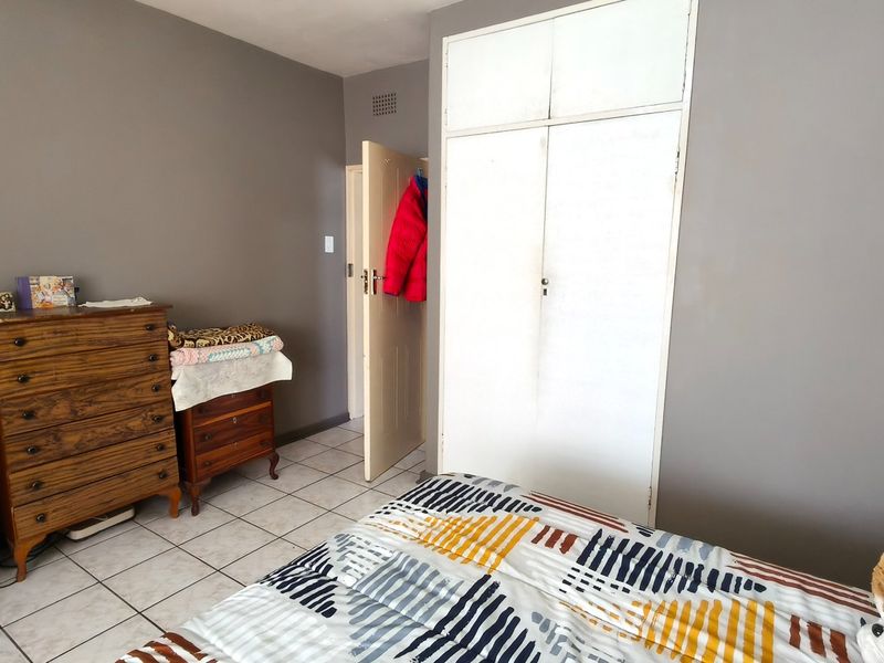 A bedroom featuring tiled flooring and a built-in wardrobe with overhead storage compartments.