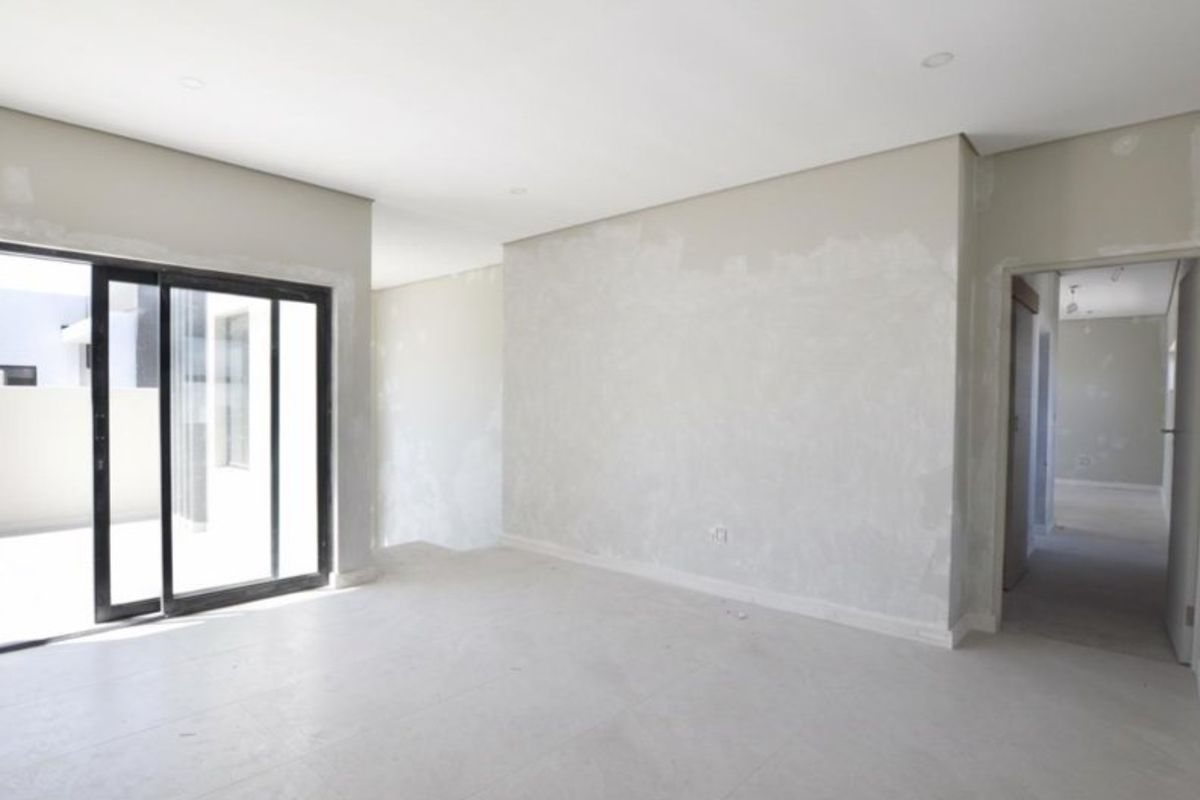An empty, unfinished living area featuring tiled floors, recessed lighting, and a large sliding glass door leading to an outdoor space.
