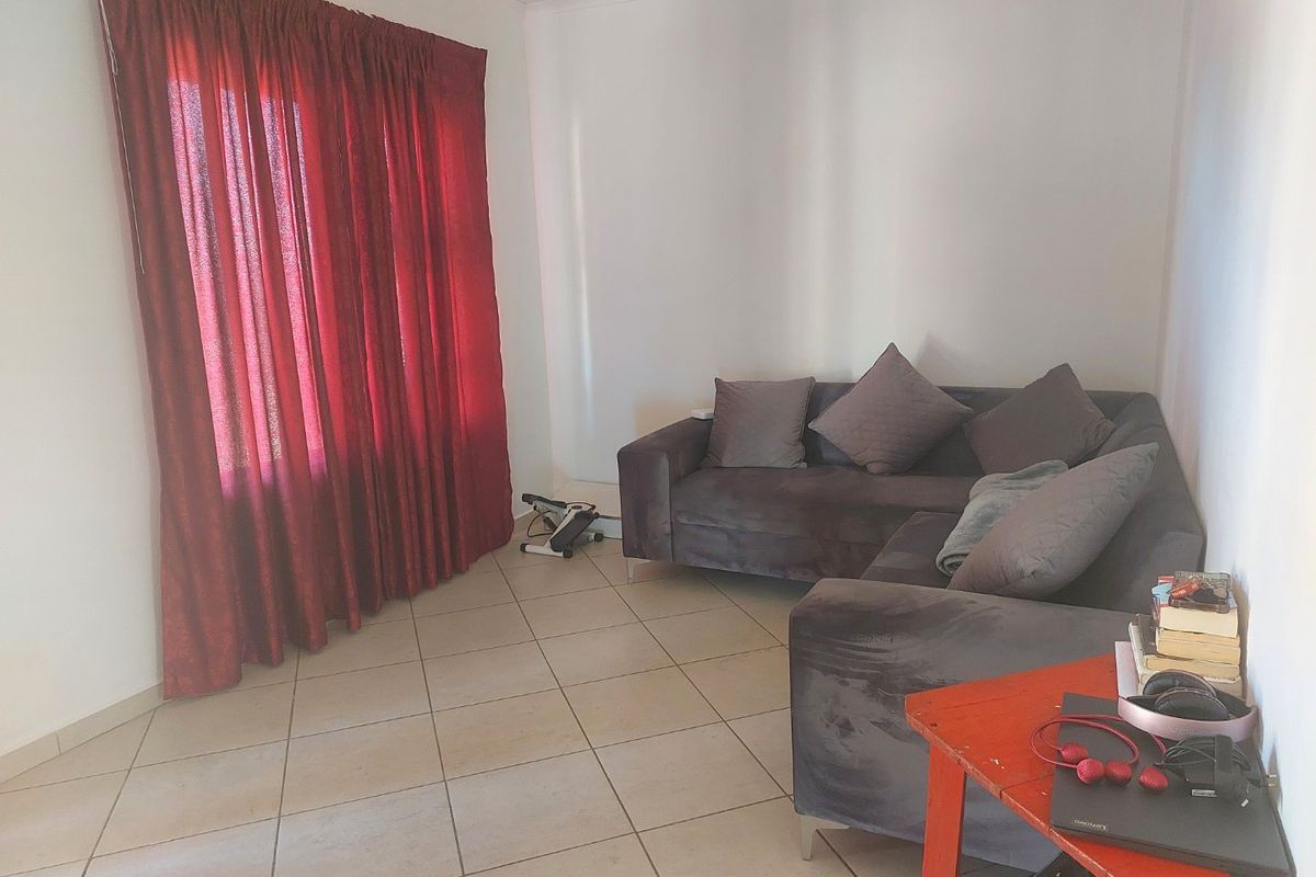 A living room featuring neutral ceramic floor tiles and large window coverage, providing a functional base for interior design updates.