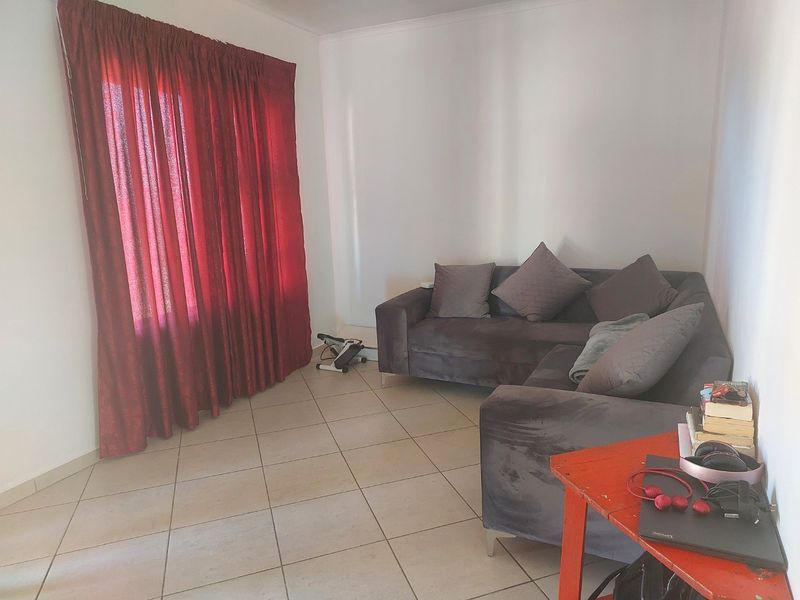 A living room featuring neutral ceramic floor tiles and large window coverage, providing a functional base for interior design updates.