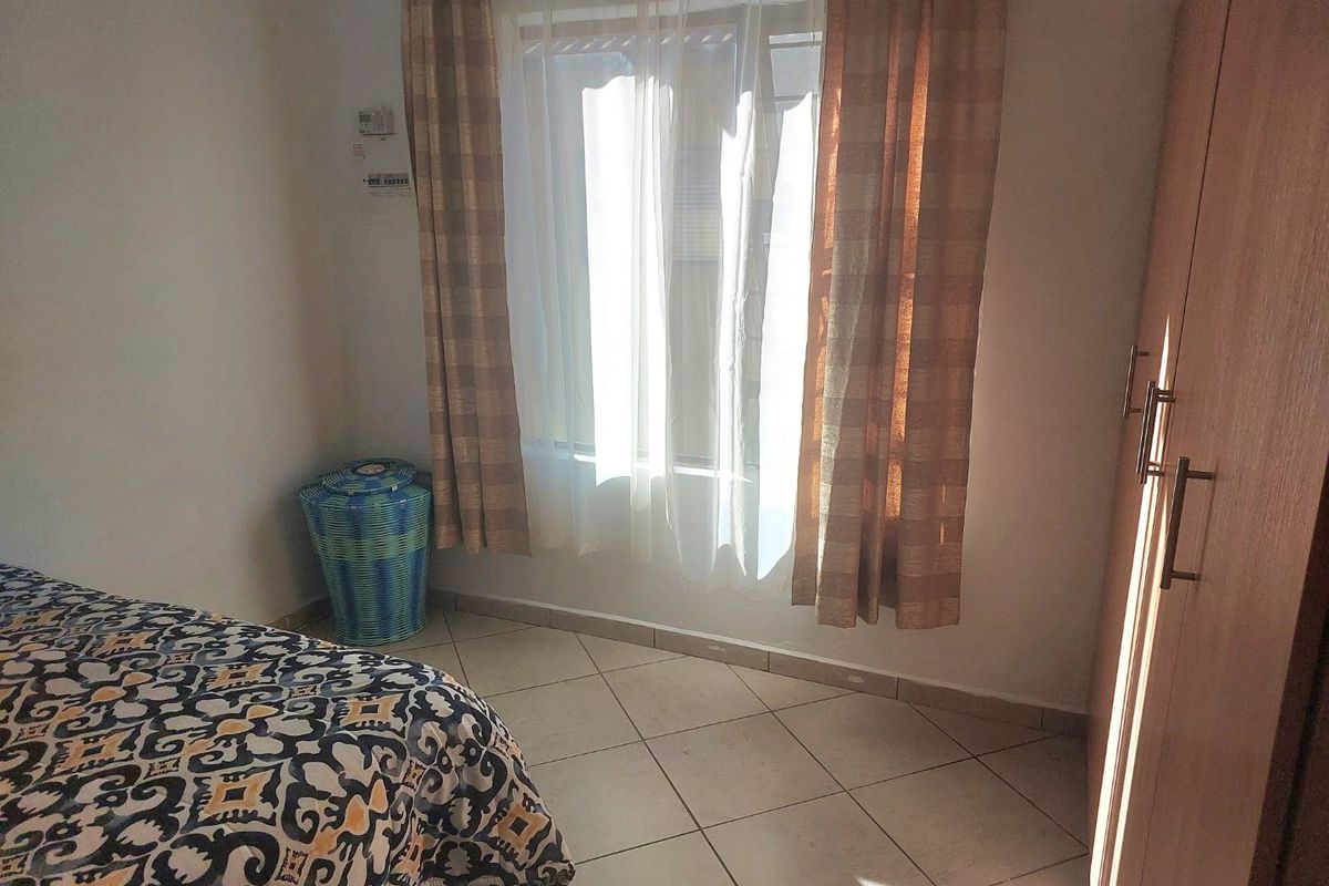 A bedroom featuring tiled flooring and a built-in wardrobe, providing functional storage space within the room.