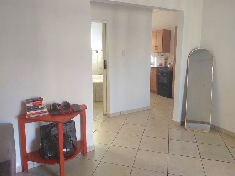 Open plan living area with tiled flooring, providing a view into the kitchen and adjacent bathroom.