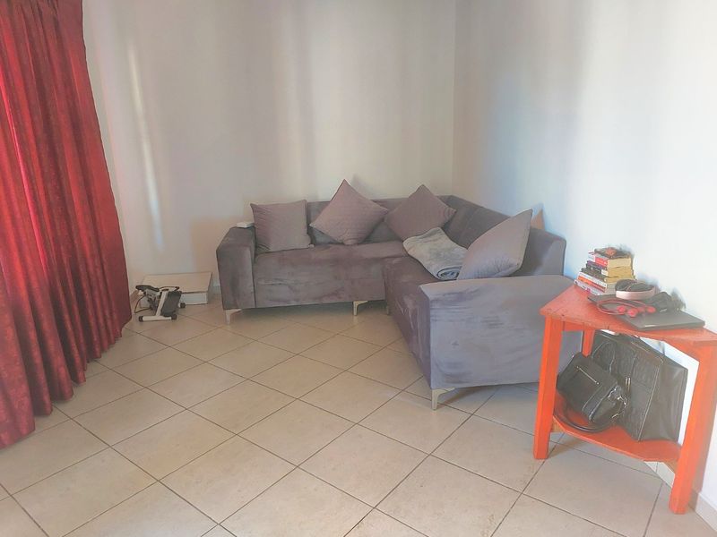 A living room area featuring neutral ceramic floor tiles and large red curtains, providing a functional space for relaxation.