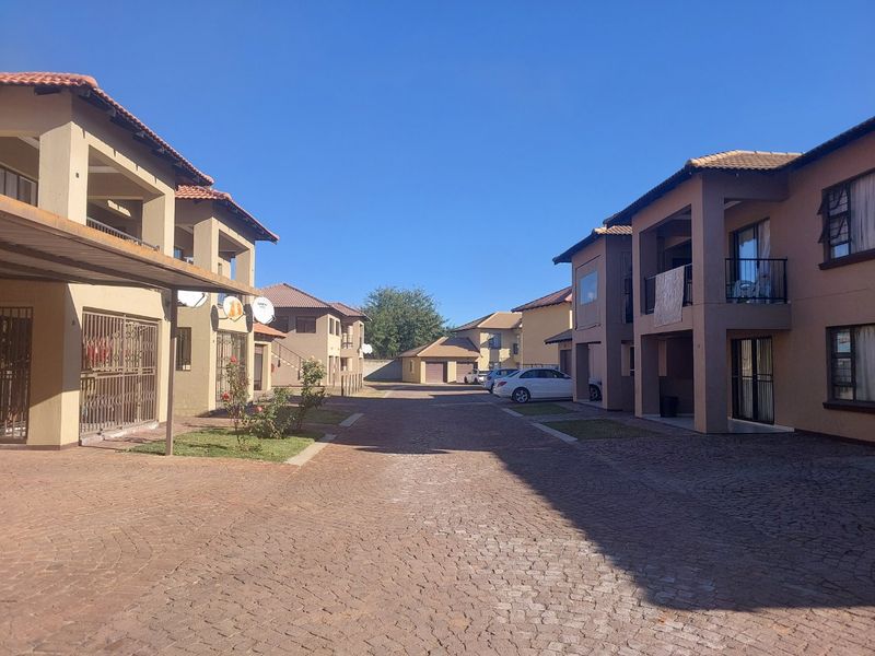 A view of the apartment complex exterior featuring paved driveways, covered parking bays, and multi-story residential units with balconies.