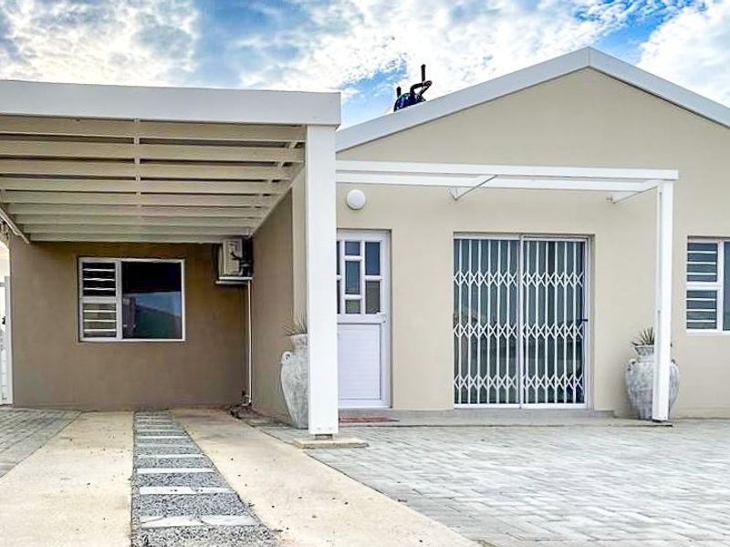 Front elevation of the townhouse featuring a paved driveway, covered carport, and secure sliding door entrance.