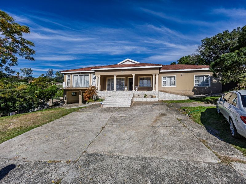 Front elevation of a single-story house featuring a covered porch with decorative columns, tiled steps, and a large concrete driveway.