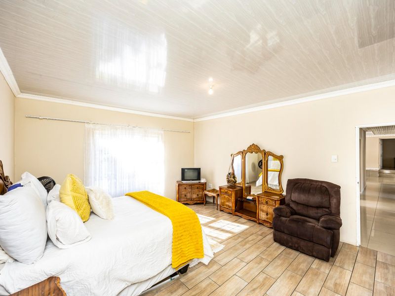 A spacious bedroom featuring tiled flooring, a glossy ceiling finish, and coving, offering a neutral base for potential interior updates.