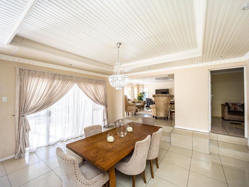 Spacious open-plan dining and living area featuring tiled floors, a decorative coffered ceiling, and a large sliding door providing natural light.