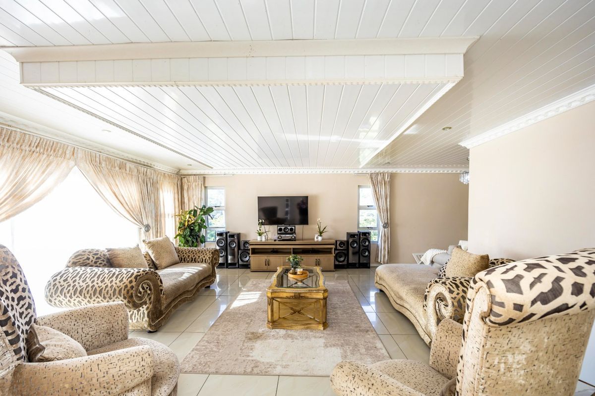 Spacious living room featuring tiled flooring, a distinctive tongue and groove ceiling with coving, and a built-in media console.