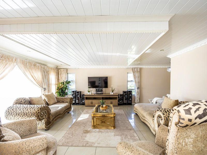 Spacious living room featuring tiled flooring, a distinctive tongue and groove ceiling with coving, and a built-in media console.