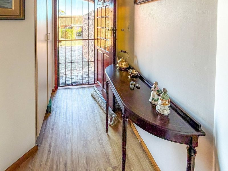 Entrance hallway featuring laminate flooring, a built-in cupboard, and a secure timber door leading to the exterior.