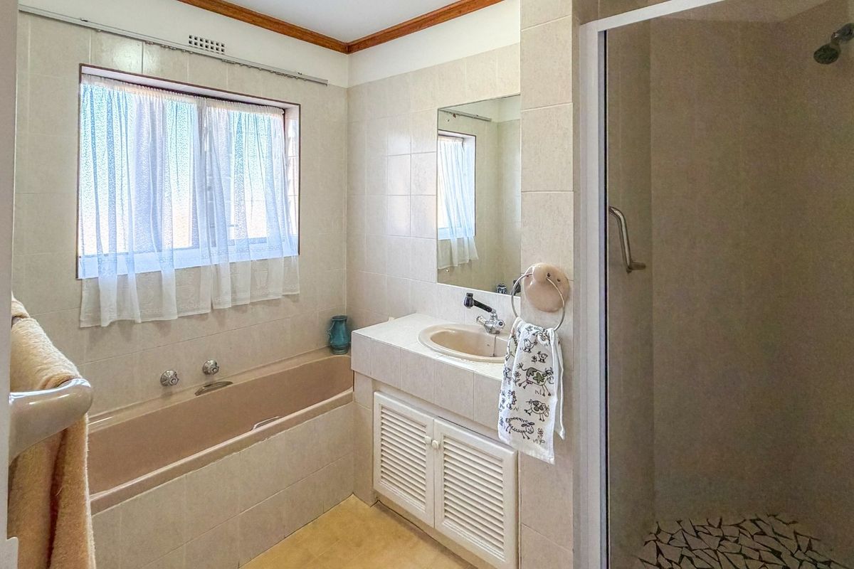 A functional bathroom featuring a built-in bathtub, a separate shower enclosure, and a vanity unit with an integrated sink.