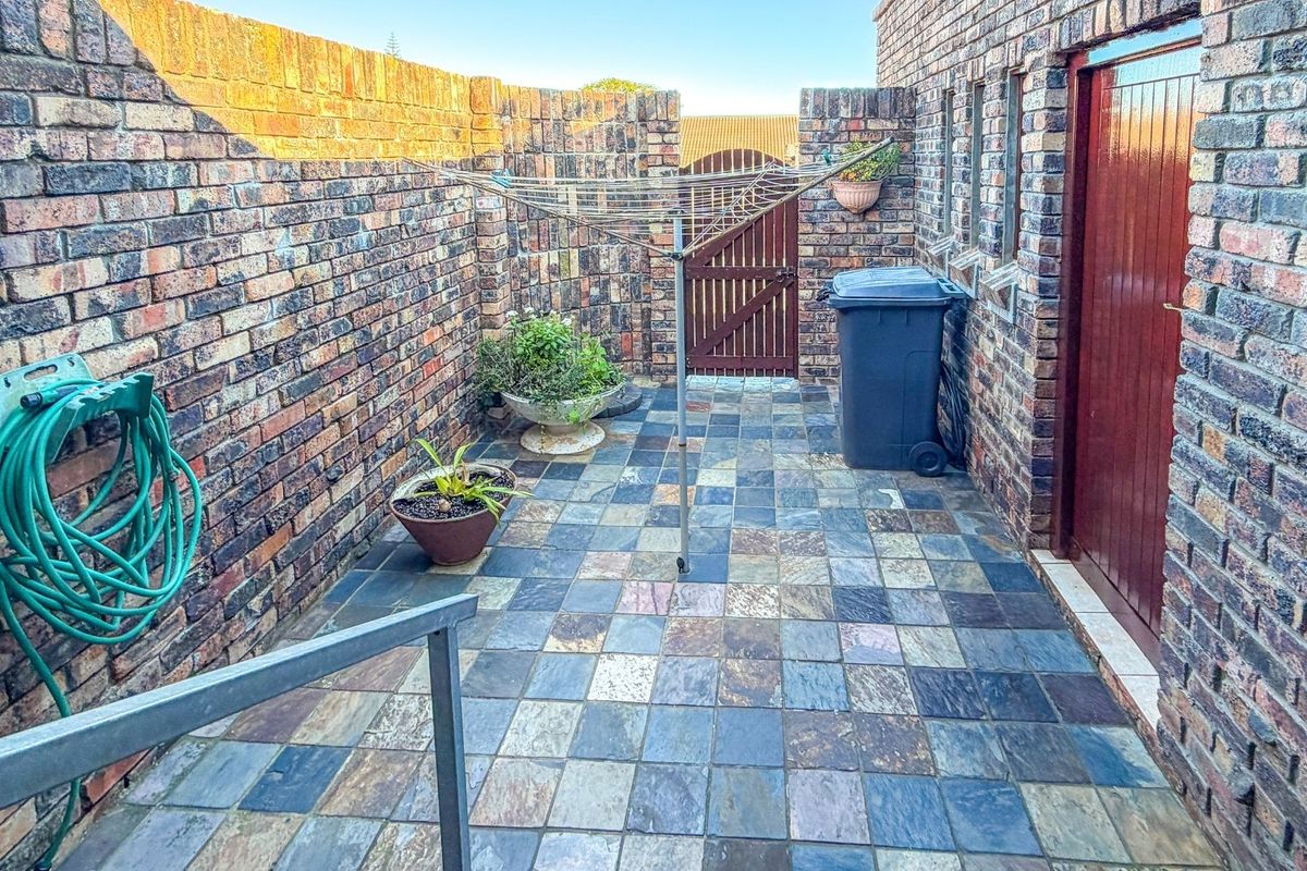 A private rear courtyard featuring durable face brick walls, slate tile flooring, and a secure timber gate access.