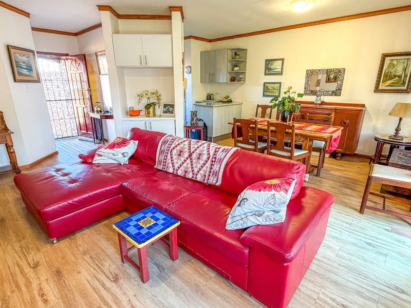 Open-plan living and dining area featuring laminate flooring, built-in cabinetry, and direct access to the exterior through a security gate.