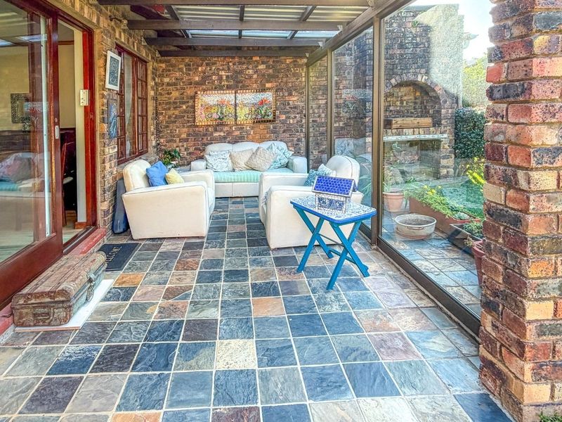 Enclosed patio featuring exposed brick walls, slate tile flooring, and a built-in brick braai, providing a versatile outdoor entertainment space.