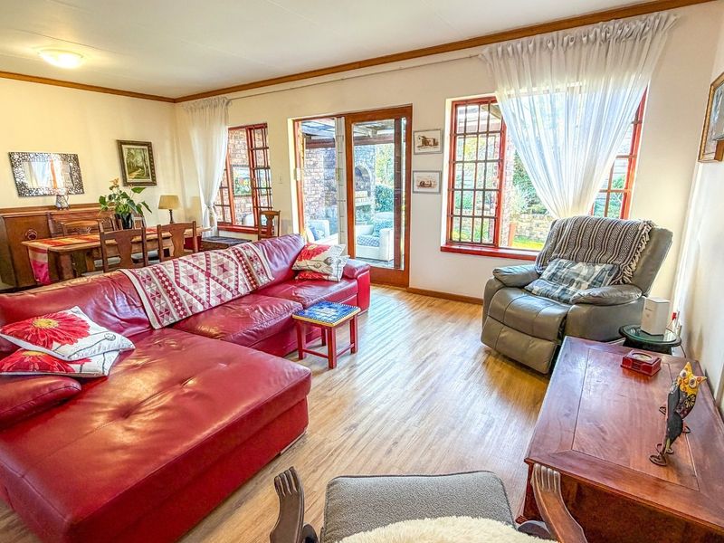 Open plan living and dining area featuring laminate flooring, wooden window frames, and direct access to an outdoor patio through a glass sliding door.