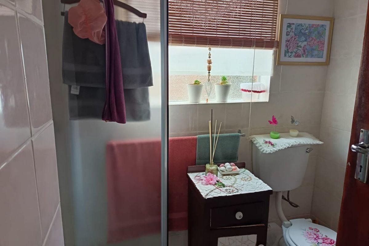 A compact bathroom featuring a shower enclosure, toilet, and tiled wall finishes, providing essential functionality in a modest space.