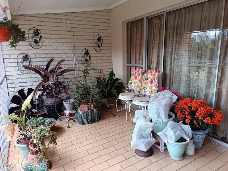 A covered patio area featuring brick wall finishes, tiled flooring, and large sliding glass doors providing access to the interior living space.