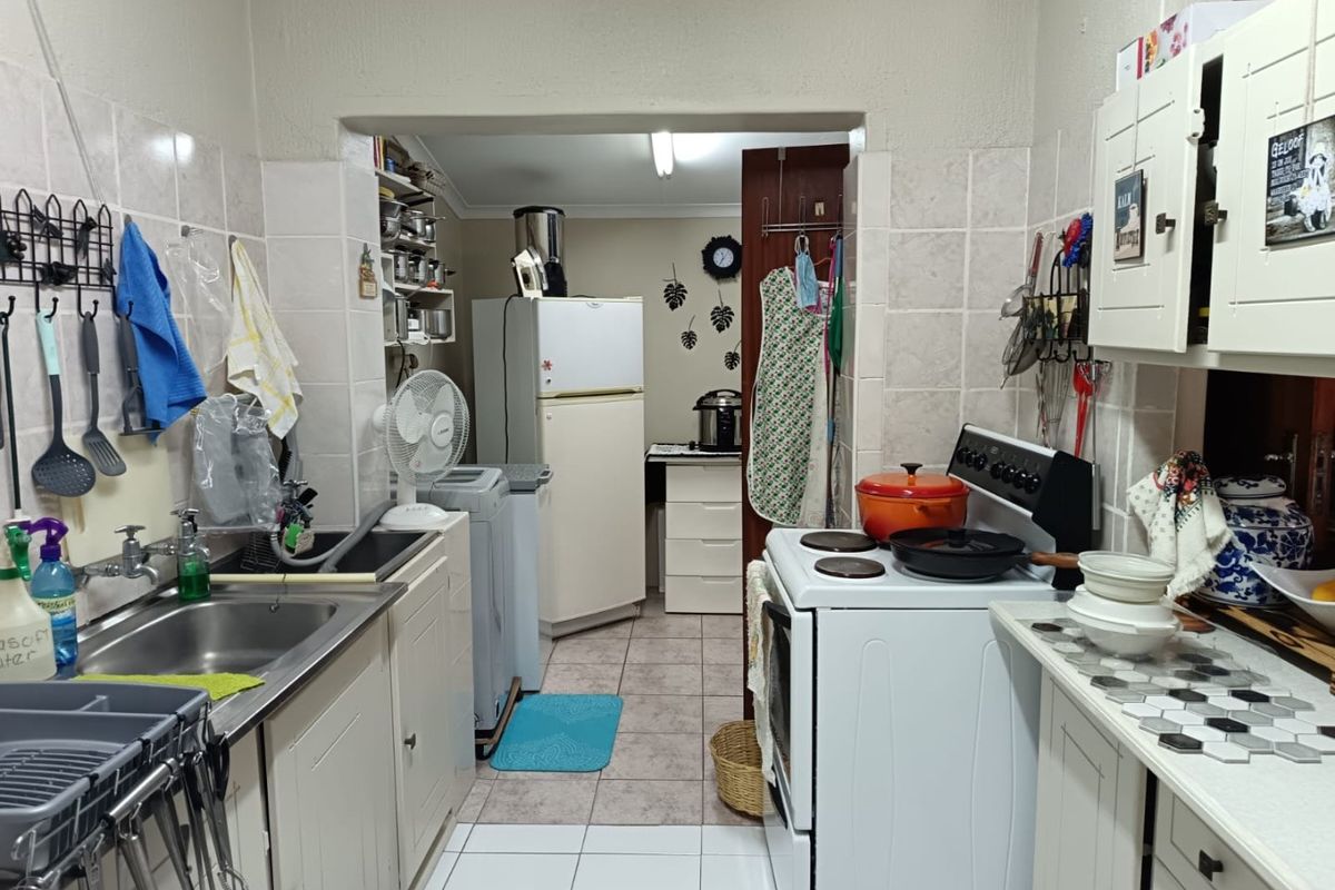 A functional kitchen featuring tiled splashbacks, built-in cabinetry, and a freestanding stove, offering potential for modernization and layout optimization.