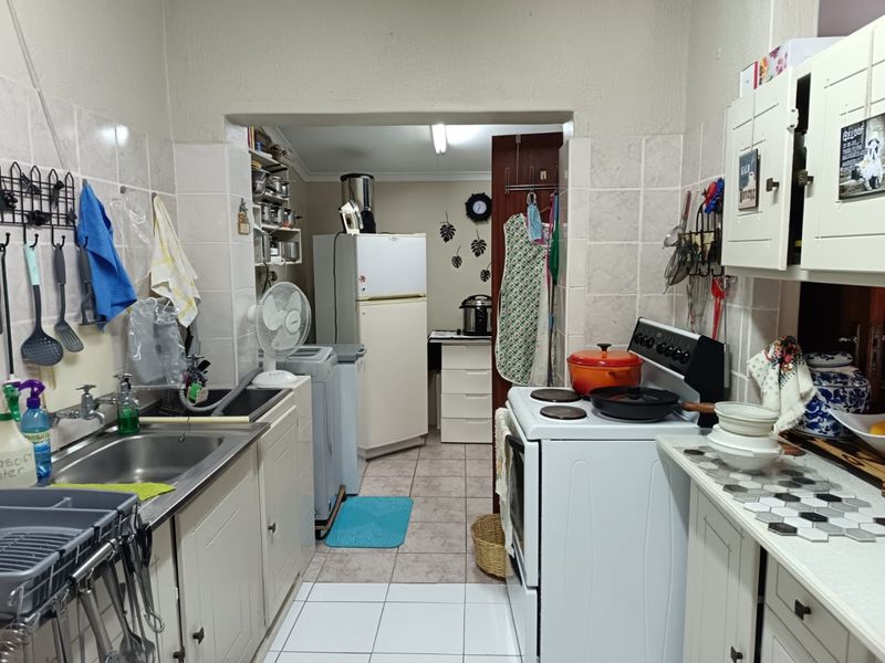 A functional kitchen featuring tiled splashbacks, built-in cabinetry, and a freestanding stove, offering potential for modernization and layout optimization.
