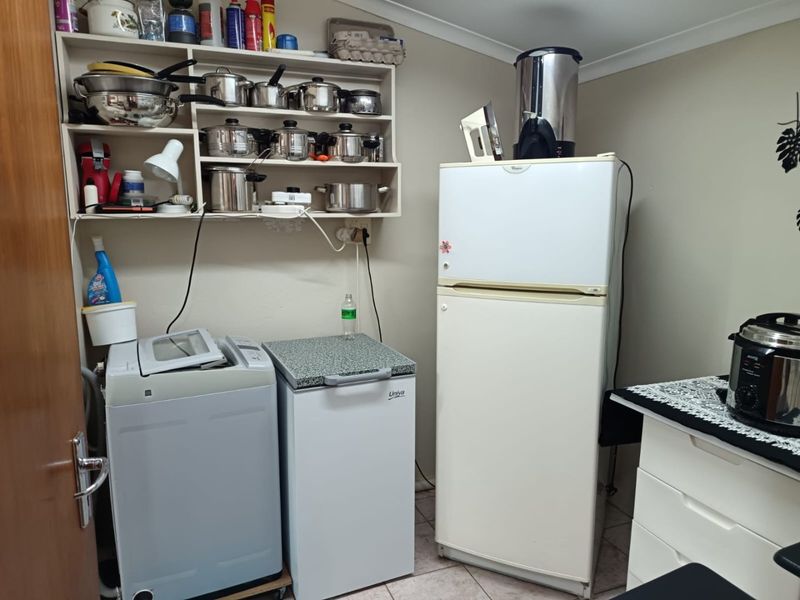 A functional laundry area featuring wall-mounted storage shelving and tiled flooring, providing space for laundry appliances and utility storage.