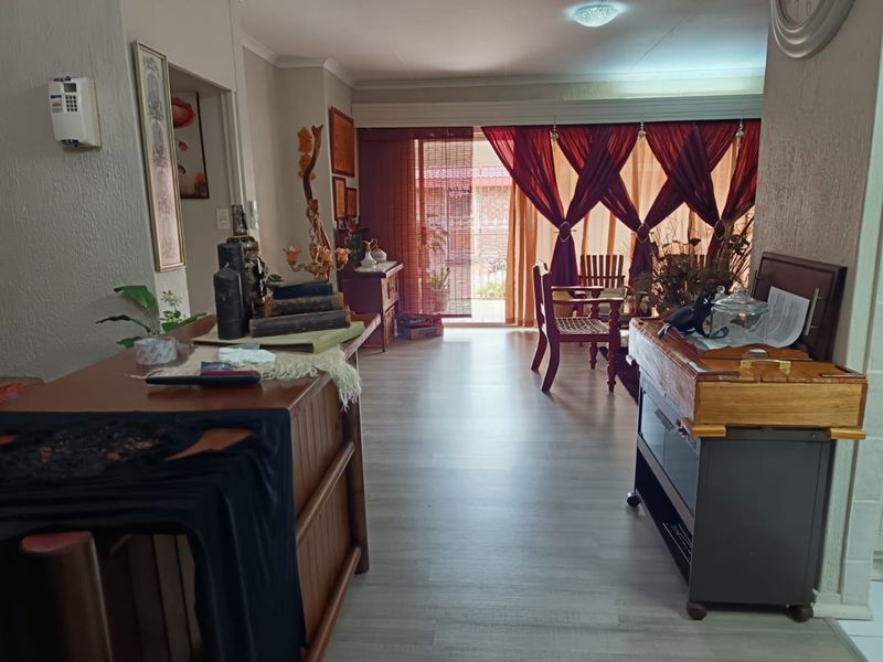 A living room area featuring light-toned laminate flooring and a large sliding glass door providing access to the outdoor space.