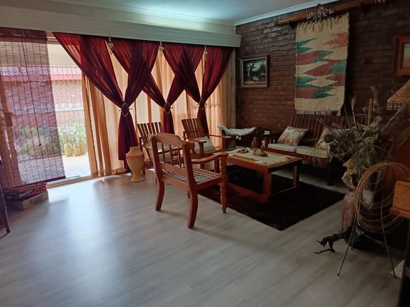 A cozy living room featuring an exposed brick feature wall, modern laminate flooring, and large sliding glass doors providing access to the patio.