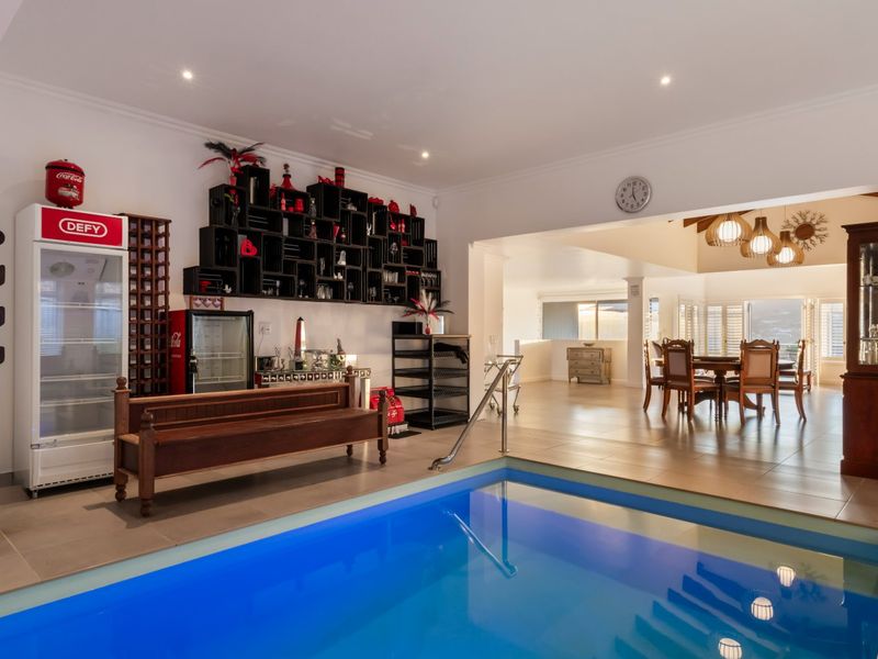 An indoor swimming pool area featuring tiled flooring and recessed lighting, seamlessly connected to an adjacent dining space.