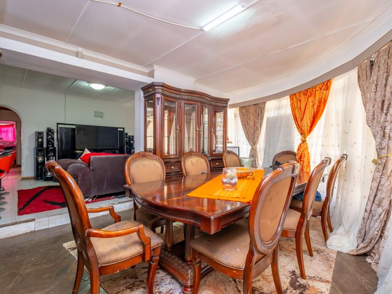 Dining room area featuring a curved wall, tiled flooring, and direct access to an adjacent living space.