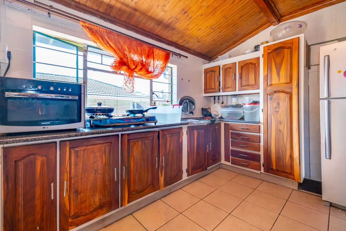 A functional kitchen featuring wooden cabinetry, granite countertops, a built-in oven, and a timber-clad ceiling with tiled flooring.