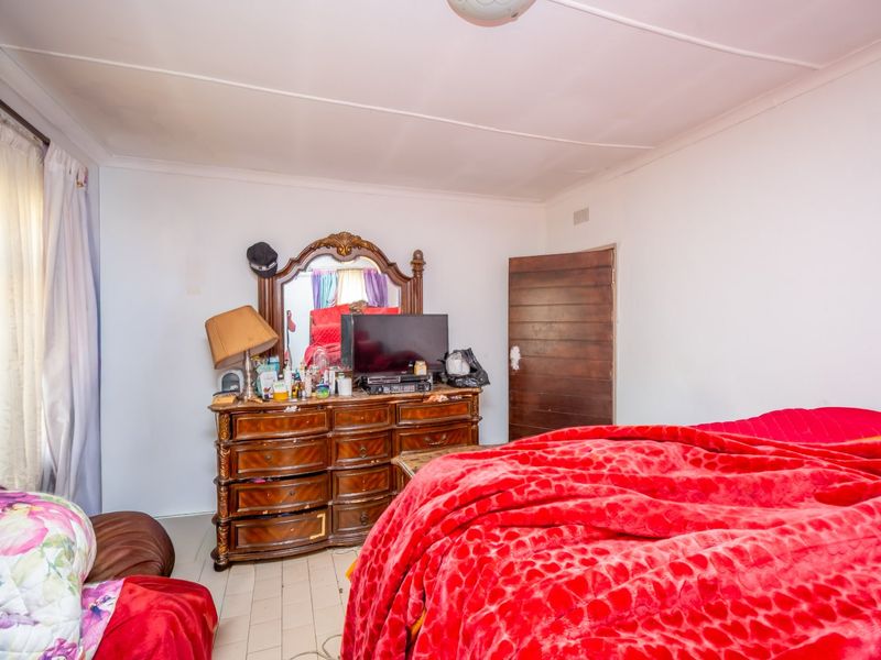 A standard bedroom featuring tiled flooring, a timber door, and a ceiling light fixture.