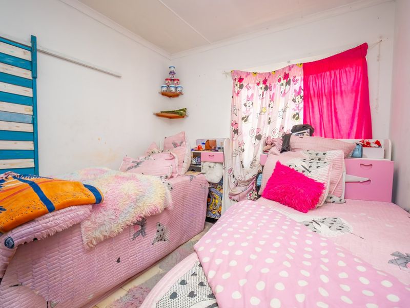 A bedroom featuring white walls and built-in shelving, currently utilized as a shared sleeping space.