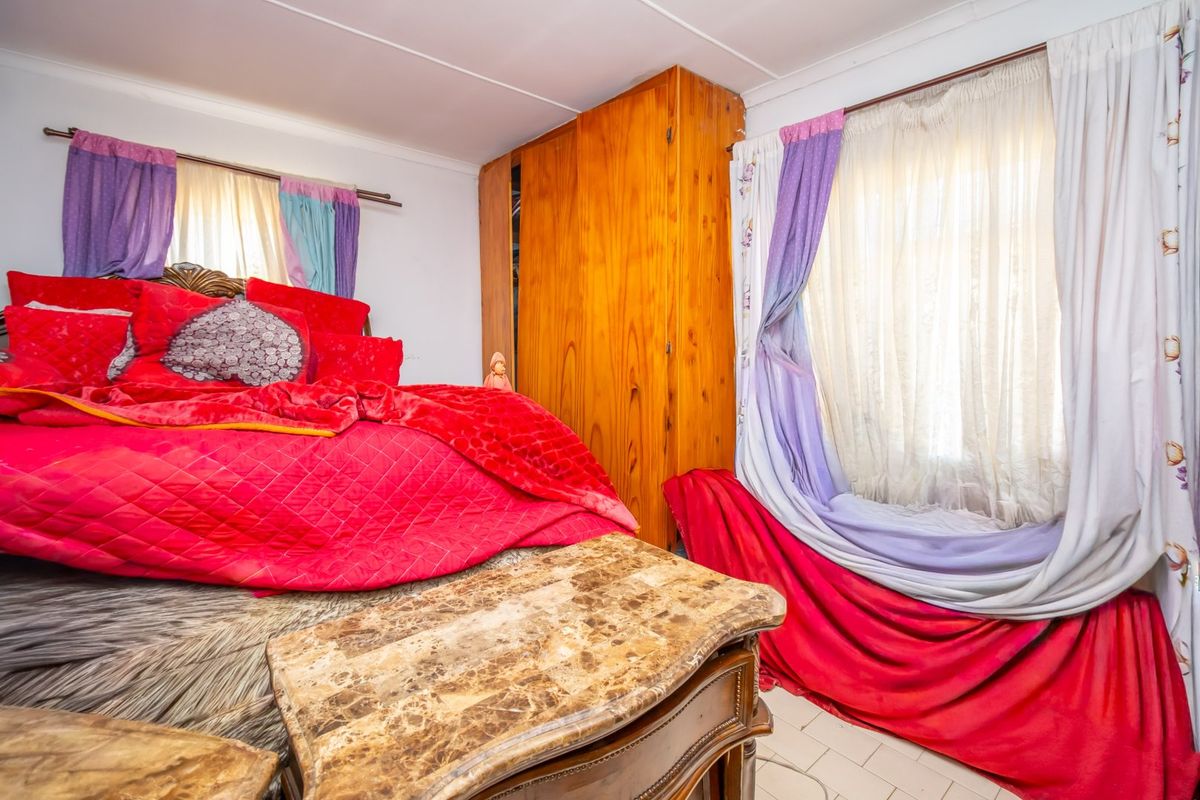 A bedroom featuring built-in wooden cabinetry and tiled flooring, offering a functional space with potential for modern updates.
