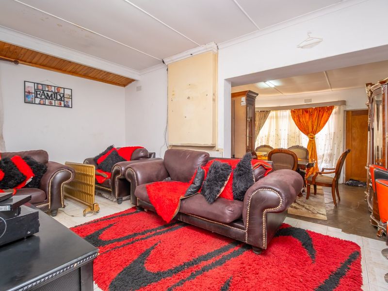 Open plan living and dining area featuring tiled flooring and a combination of standard and timber-paneled ceilings, requiring cosmetic updates to wall finishes.