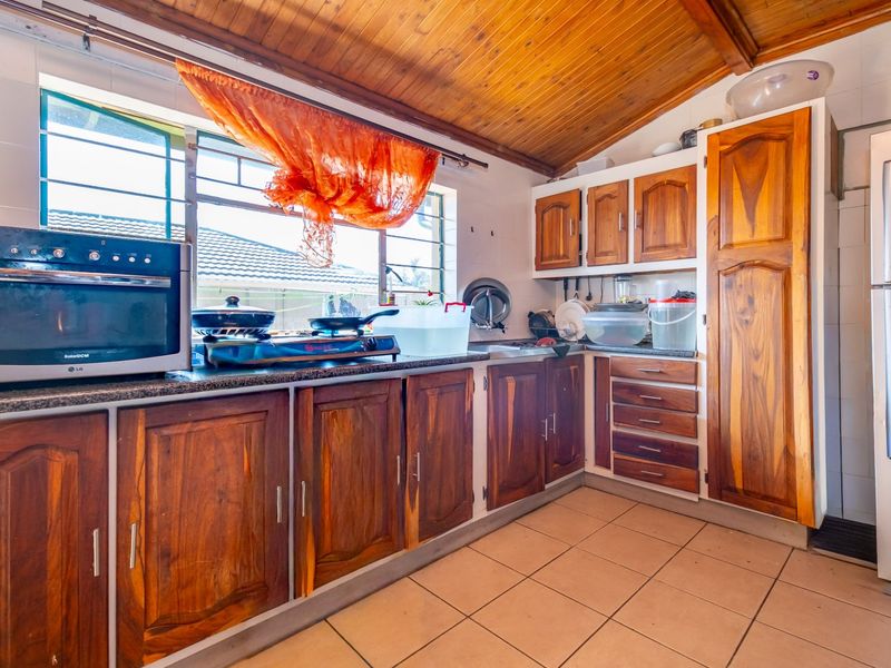 A functional kitchen featuring wooden cabinetry, granite countertops, a built-in oven, and a timber-clad ceiling with tiled flooring.