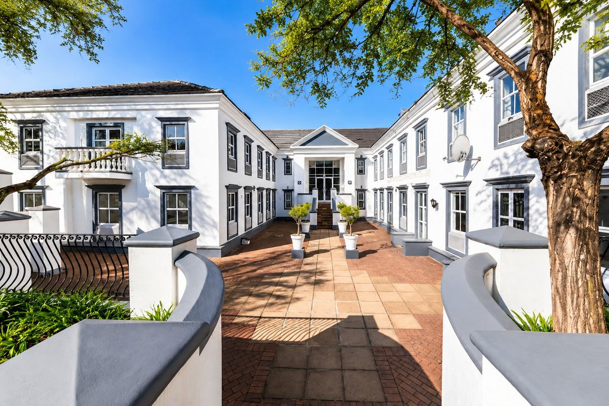 A well-maintained commercial courtyard featuring paved flooring, a central walkway, and a multi-story building facade with classic architectural detailing.
