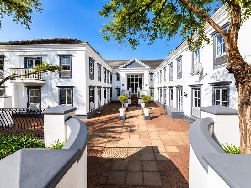 A well-maintained commercial courtyard featuring paved flooring, a central walkway, and a multi-story building facade with classic architectural detailing.