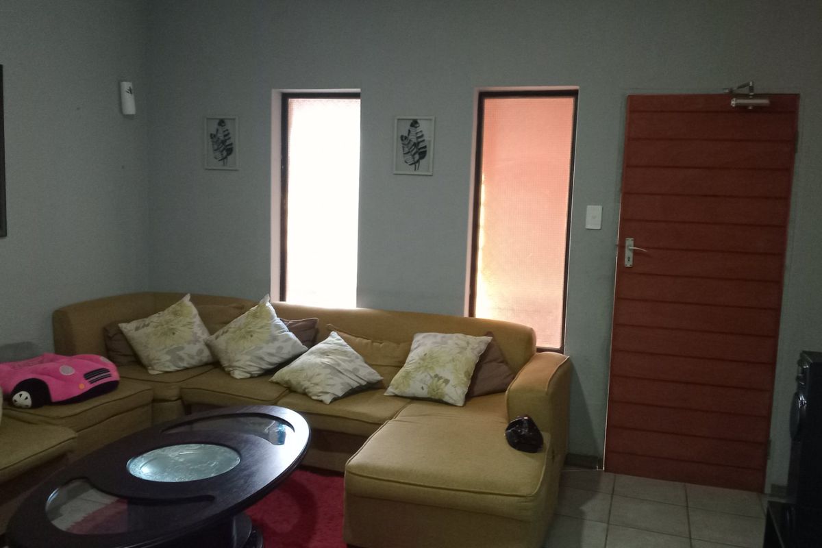A living room area featuring tiled flooring, vertical windows, and a horizontal slat door, providing a functional space for relaxation.
