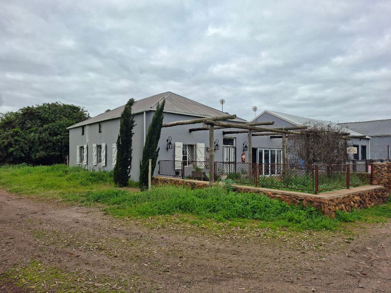 Rear view of the property featuring a timber pergola, stone retaining wall, and security shutters, set against a large garden area.