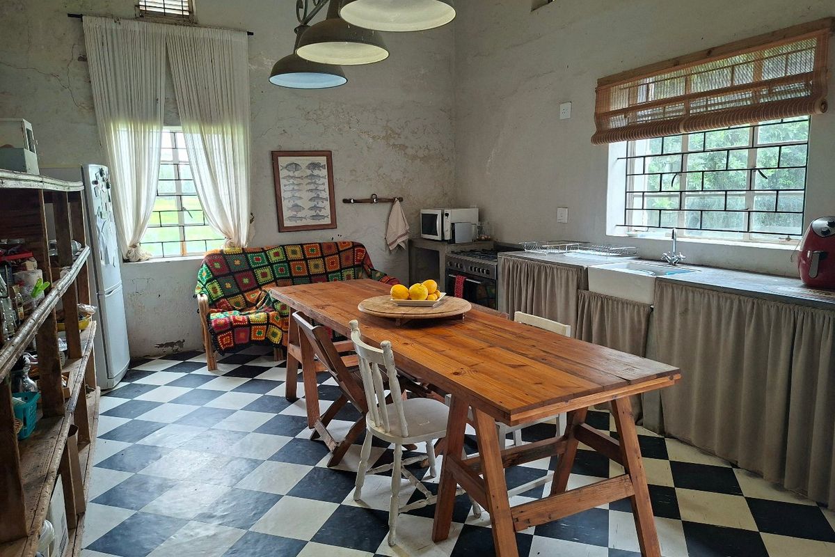 Rustic kitchen featuring a farmhouse sink, gas stove, and distinctive checkerboard flooring, with high ceilings and exposed wall textures.