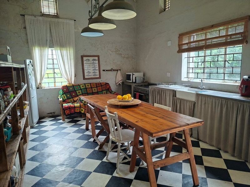 Rustic kitchen featuring a farmhouse sink, gas stove, and distinctive checkerboard flooring, with high ceilings and exposed wall textures.