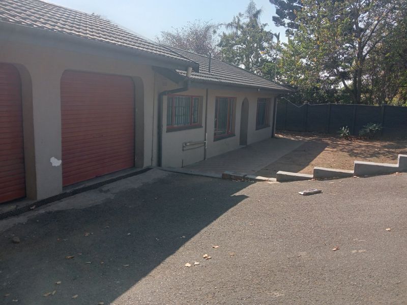 Front exterior view of the property featuring a double garage with roller shutter doors, paved driveway, and security-fitted windows.
