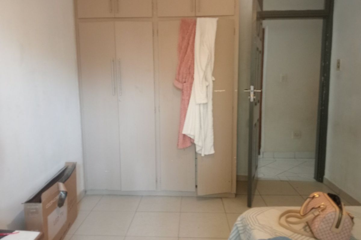 A bedroom featuring built-in cupboards and tiled flooring, providing functional storage space with potential for cosmetic updates.